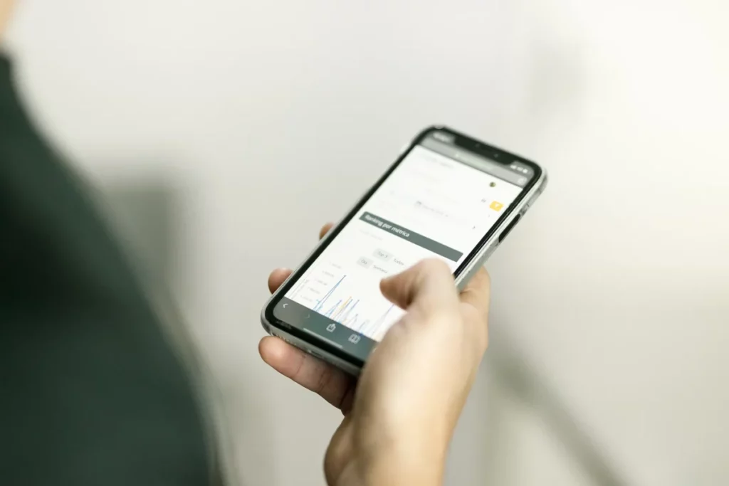 Imagem com close de uma mão segurando um celular, na tela está o sistema SimplesVet aberto.